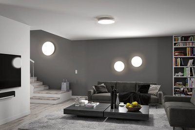 Modern living room with gray wall, gray sofa, and round white LED ceiling and wall lights for ambient lighting