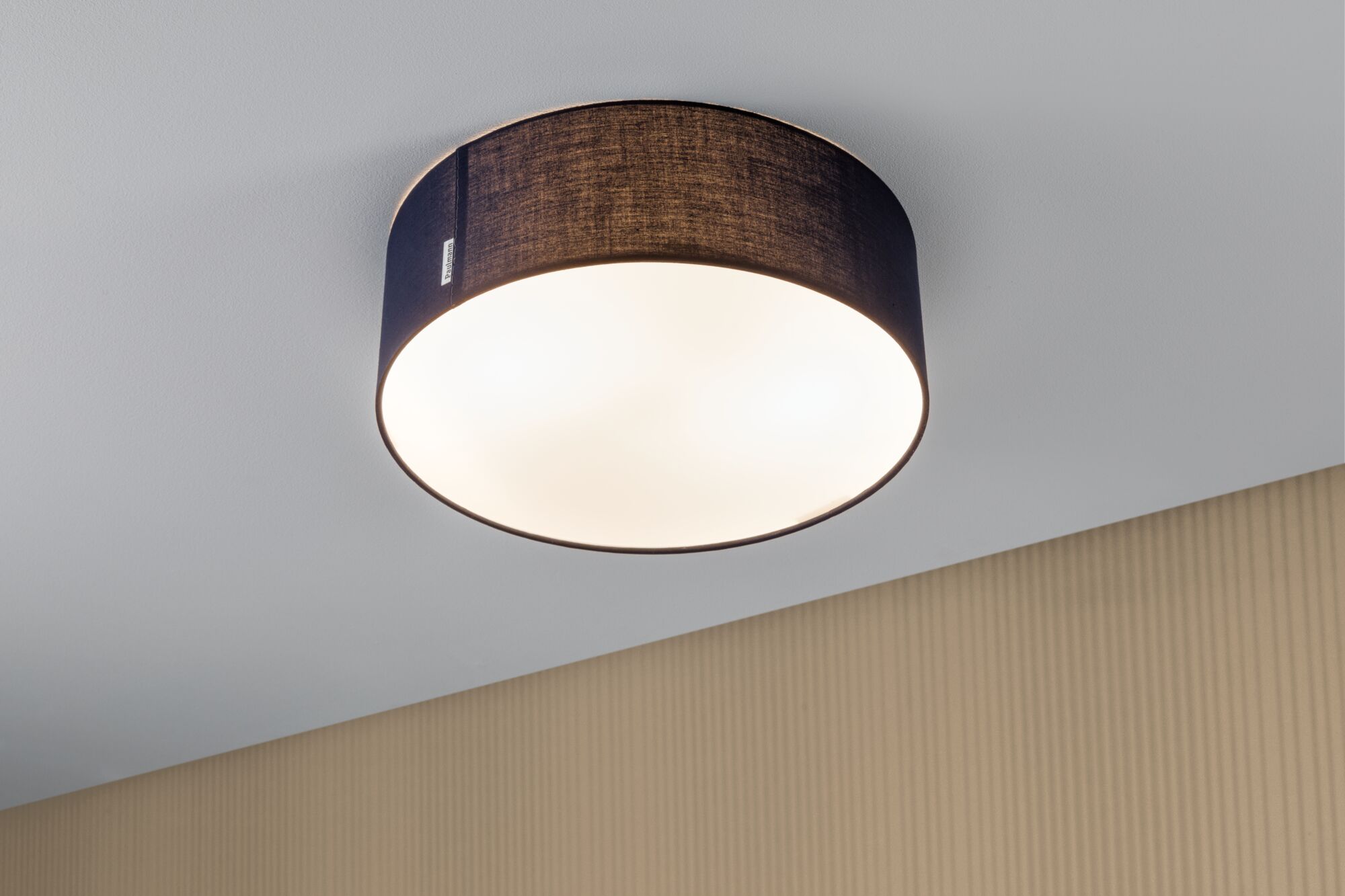 Round ceiling light with black fabric shade and warm white light for modern living spaces
