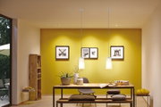 Modern dining area with wooden table, grey chair, yellow wall, and two white glass pendant lights.