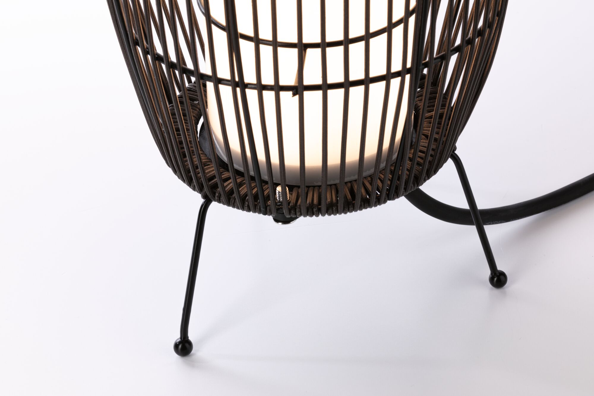Gros plan sur un pied en métal noir avec abat-jour tissé et ampoule LED blanche pour éclairage moderne.