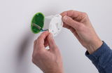 Mains installant une boîte de jonction électrique blanche en plastique avec insert vert sur mur blanc pour éclairage