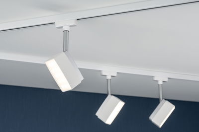 Drei weiße LED-Strahler mit silbernem Stab an weißer Schiene für moderne Deckenbeleuchtung