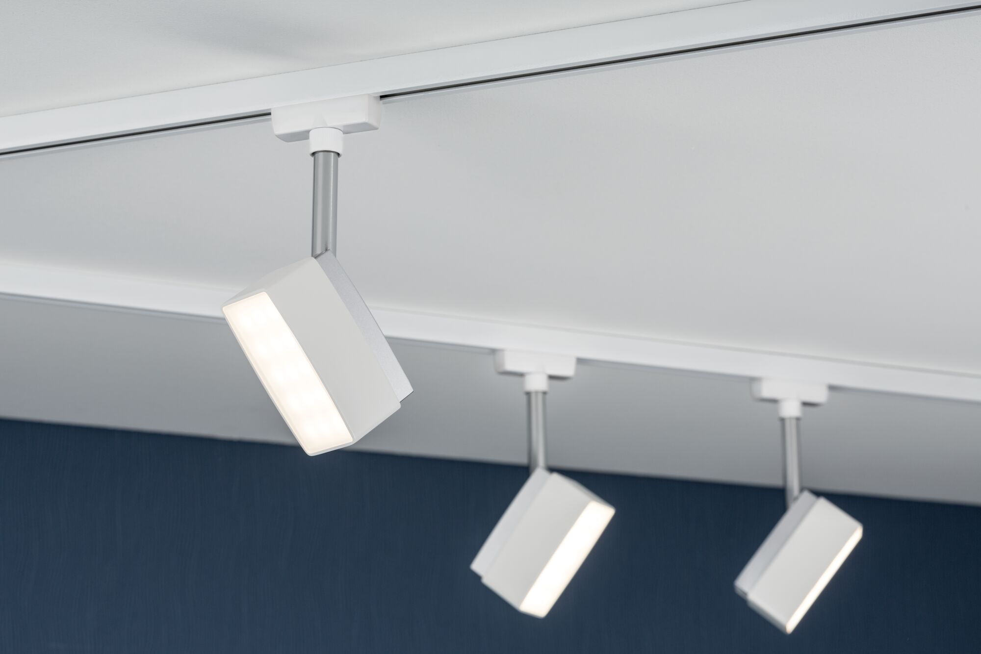 Drei weiße LED-Strahler mit silbernem Stab an weißer Schiene für moderne Deckenbeleuchtung