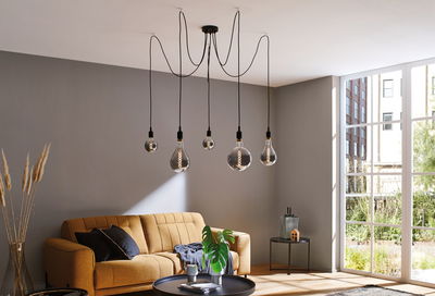 Modern living room lighting with five hanging bulbs and brown sofa against grey wall