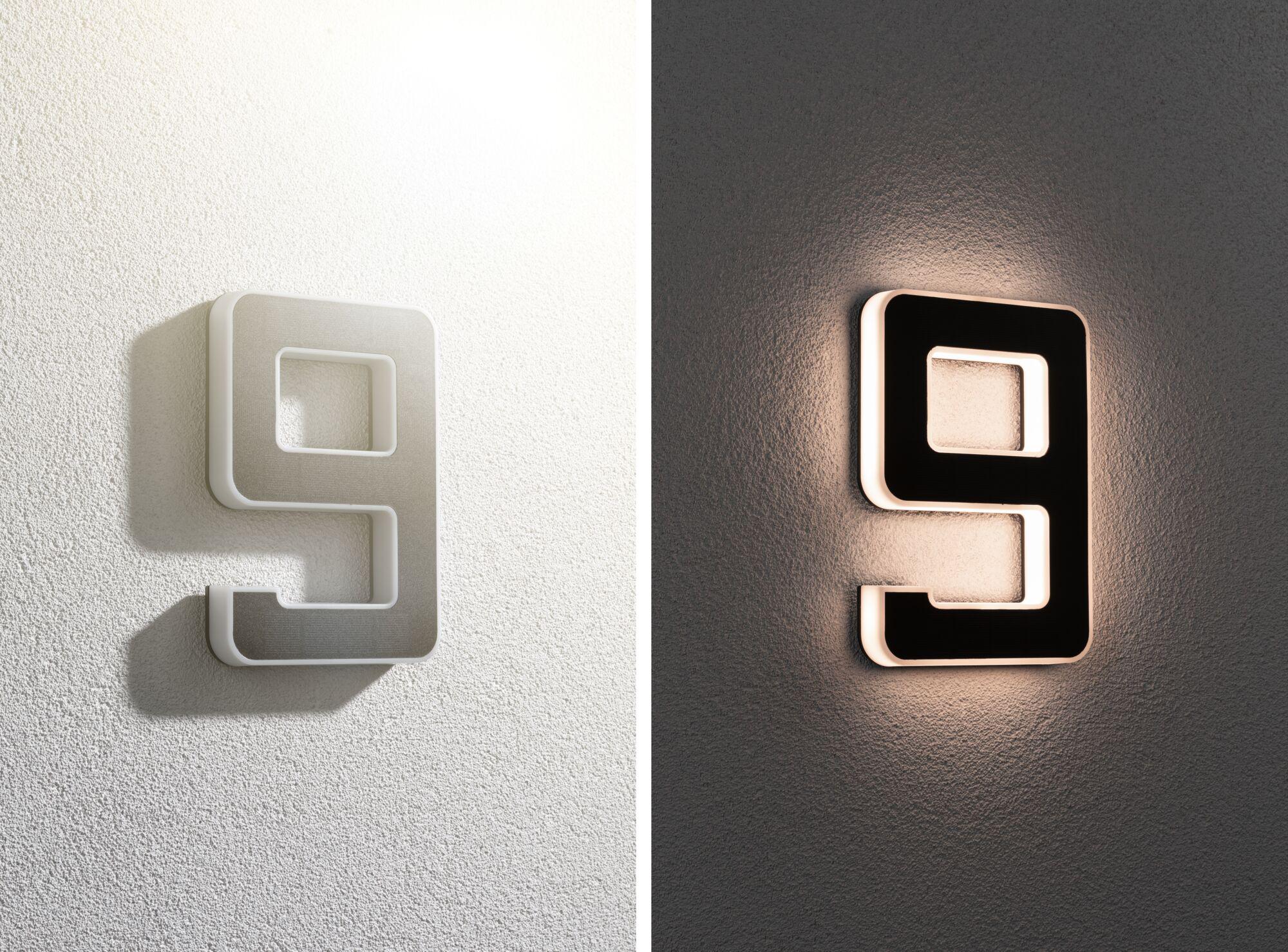 Modern LED wall light shaped as number 9, white and black, emitting warm light for home decor