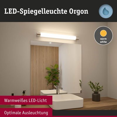LED-Spiegelleuchte Orgon mit warmweißem Licht über weißem Waschbecken und Holzablage im Bad
