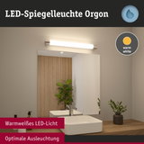 LED-Spiegelleuchte Orgon mit warmweißem Licht über weißem Waschbecken und Holzablage im Bad