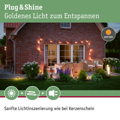 Gemütliche Terrasse mit goldener Lichterkette an roter Backsteinwand für entspannte Außenbeleuchtung