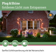 Gemütliche Terrasse mit goldener Lichterkette an roter Backsteinwand für entspannte Außenbeleuchtung