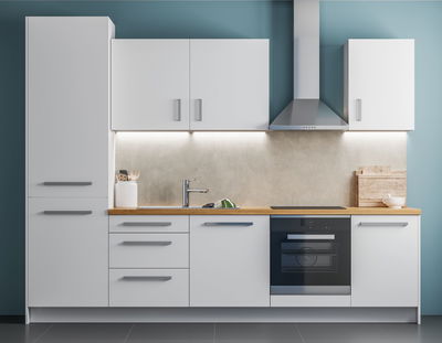 Cuisine moderne blanche avec plan de travail en bois, hotte en acier inoxydable et éclairage LED sous les meubles