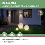 Trois lampes sphériques blanches en plastique avec lumière blanc chaud dans un jardin moderne