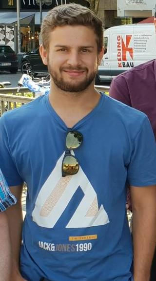 Junger Mann mit blauem Baumwoll-T-Shirt und Sonnenbrille vor urbanem Hintergrund ohne Produktbezug