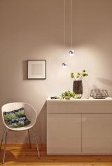 Commode blanche moderne laquée avec décoration, deux suspensions rondes et chaise blanche avec coussin coloré