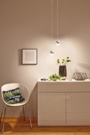 Moderne Pendelleuchten mit Kugelform in Chrom und Weiß beleuchten minimalistische Wohnzimmereinrichtung mit Pflanzen.