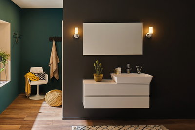 Salle de bain moderne avec lavabo blanc et meuble sur mur sombre, éclairée par des appliques LED.