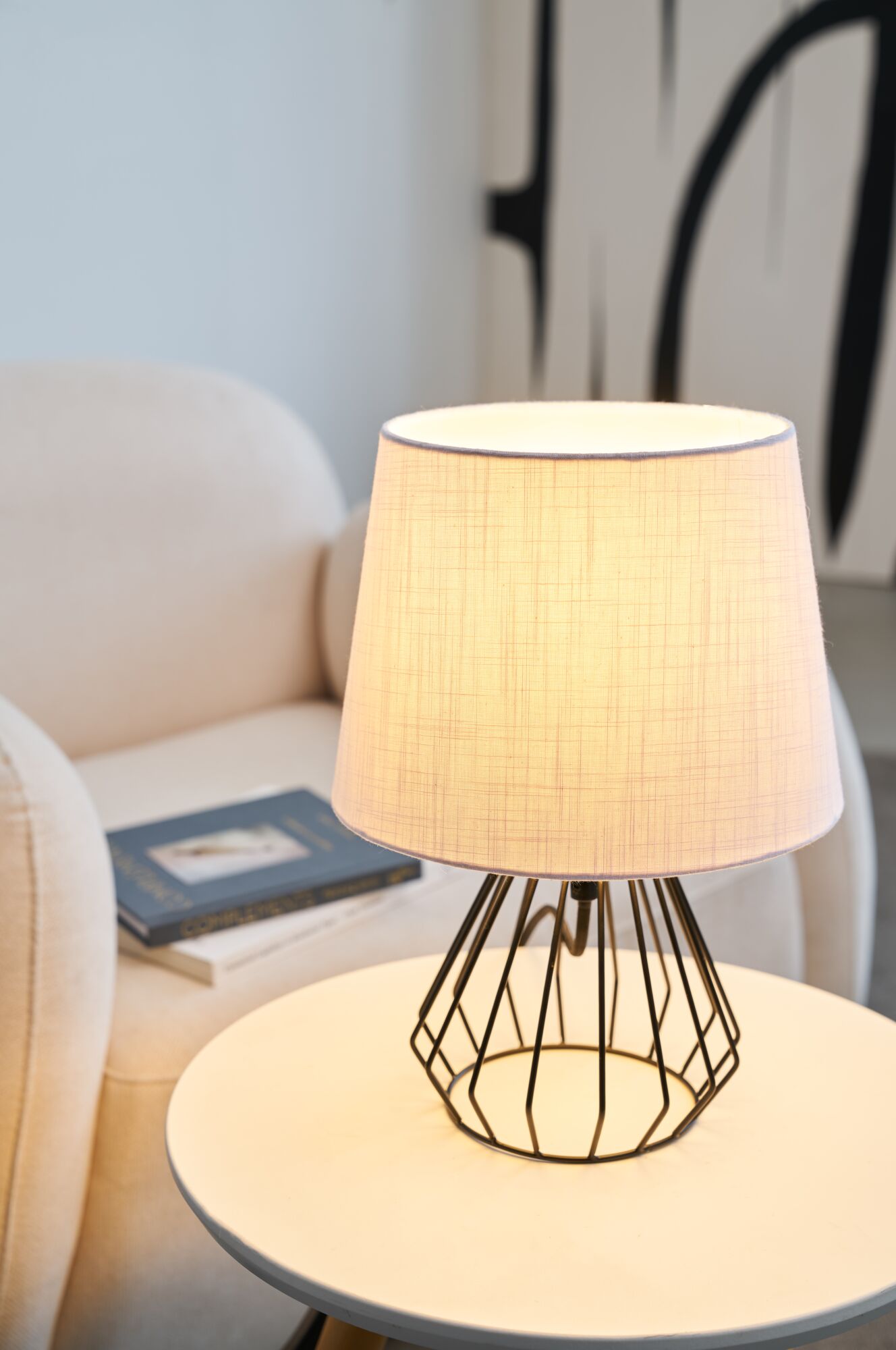 Tischlampe mit weißem Stoffschirm und schwarzem Metallgestell auf rundem Beistelltisch im Wohnzimmer
