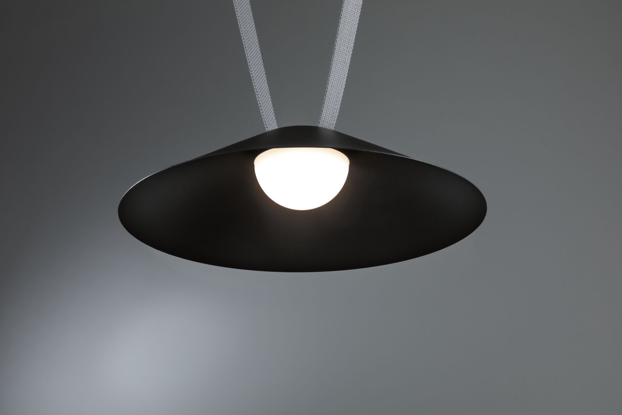 Black metal pendant lamp with round white light source for modern interior lighting