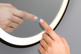Round LED mirror light with touch-sensitive switch and warm white illumination on grey wall