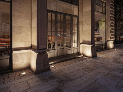 Außenbeleuchtung mit eingelassenen Bodenspots an Sandsteinfassade eines Cafés für stimmungsvolle Akzente